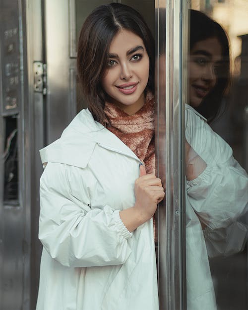 Woman in White Coat Standing Beside Glass Window