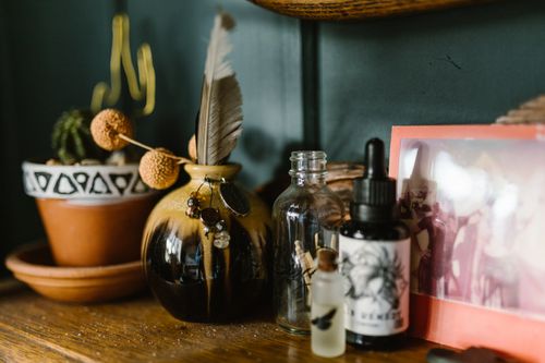 Free Artistic still life featuring glass bottles, a decorative vase, and a photo frame on a wooden shelf. Stock Photo