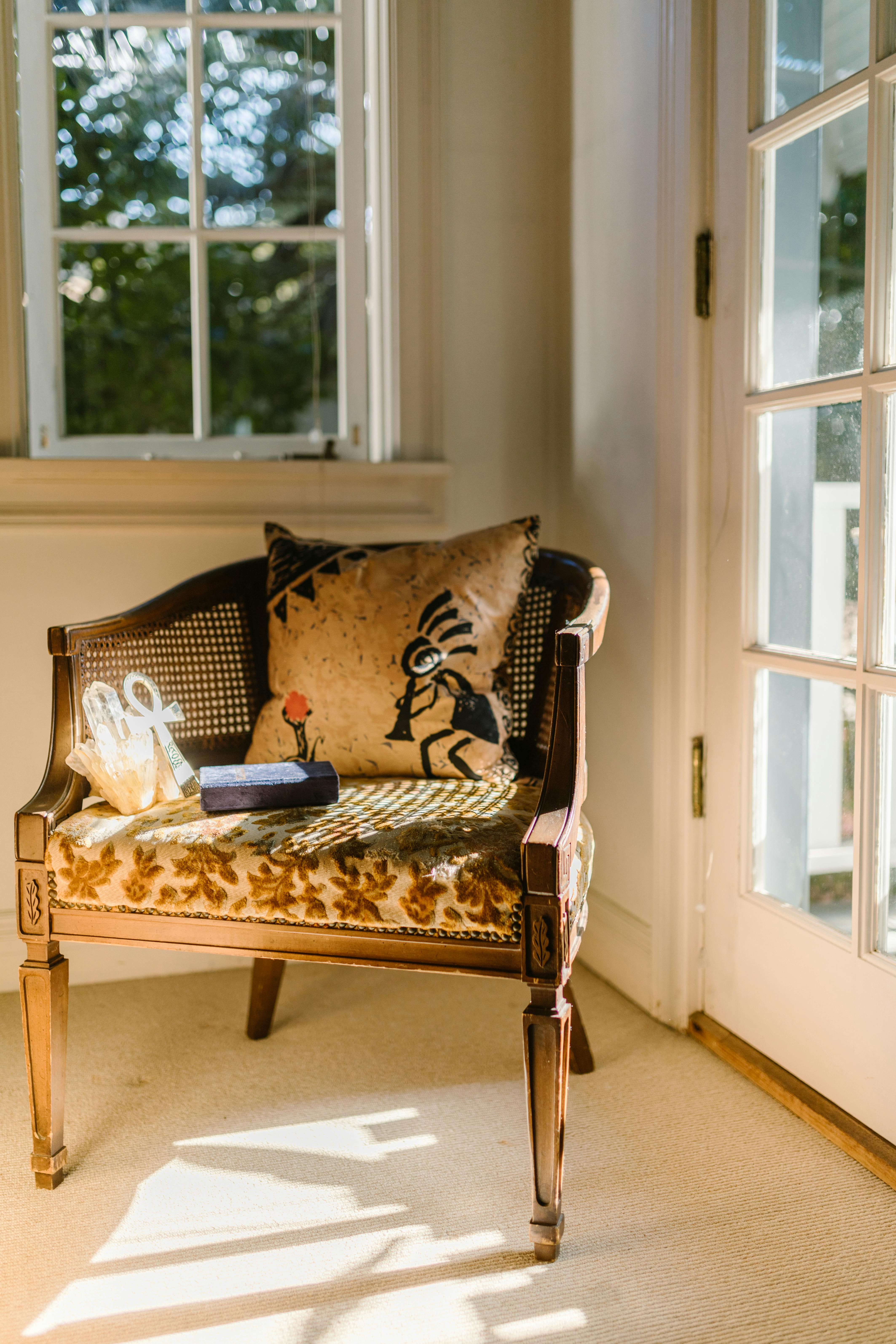 Free Elegant wooden chair with decorative pillow and gifts by a sunny window. Stock Photo