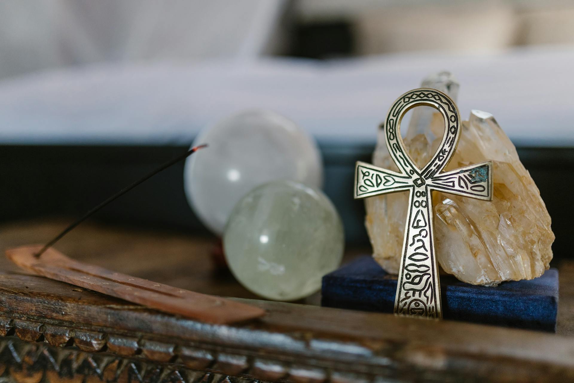 Symbol of life Ankh with crystals and incense on wooden table.