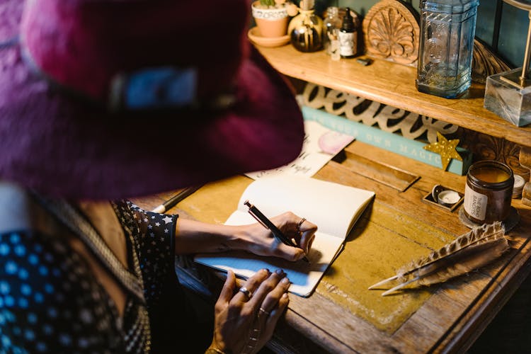 A Person Writing On A Notebook