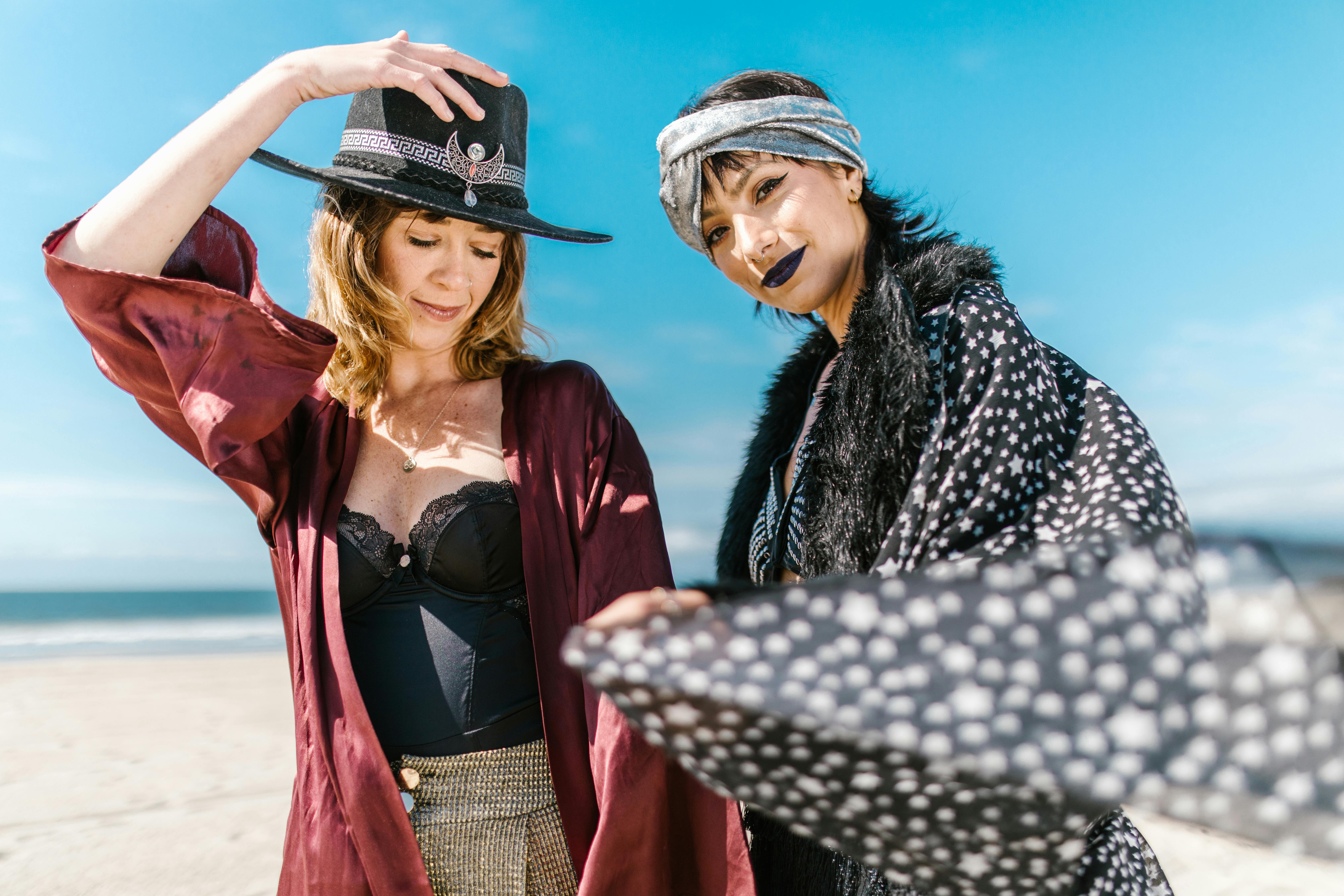 2 women in black and white coat and red coat standing on beach