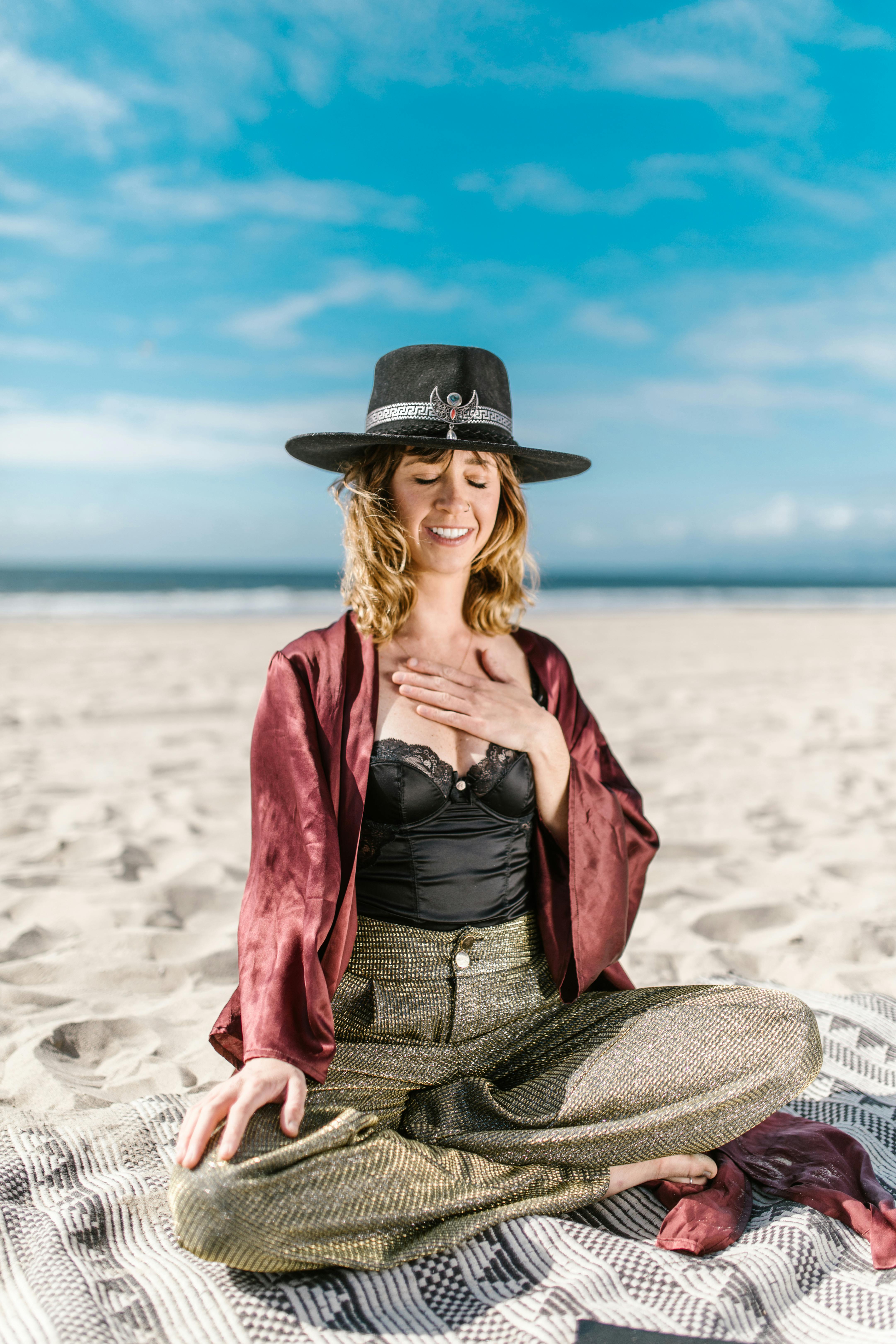 女人闭着眼睛在阳光明媚的海滩上冥想，拥抱宁静