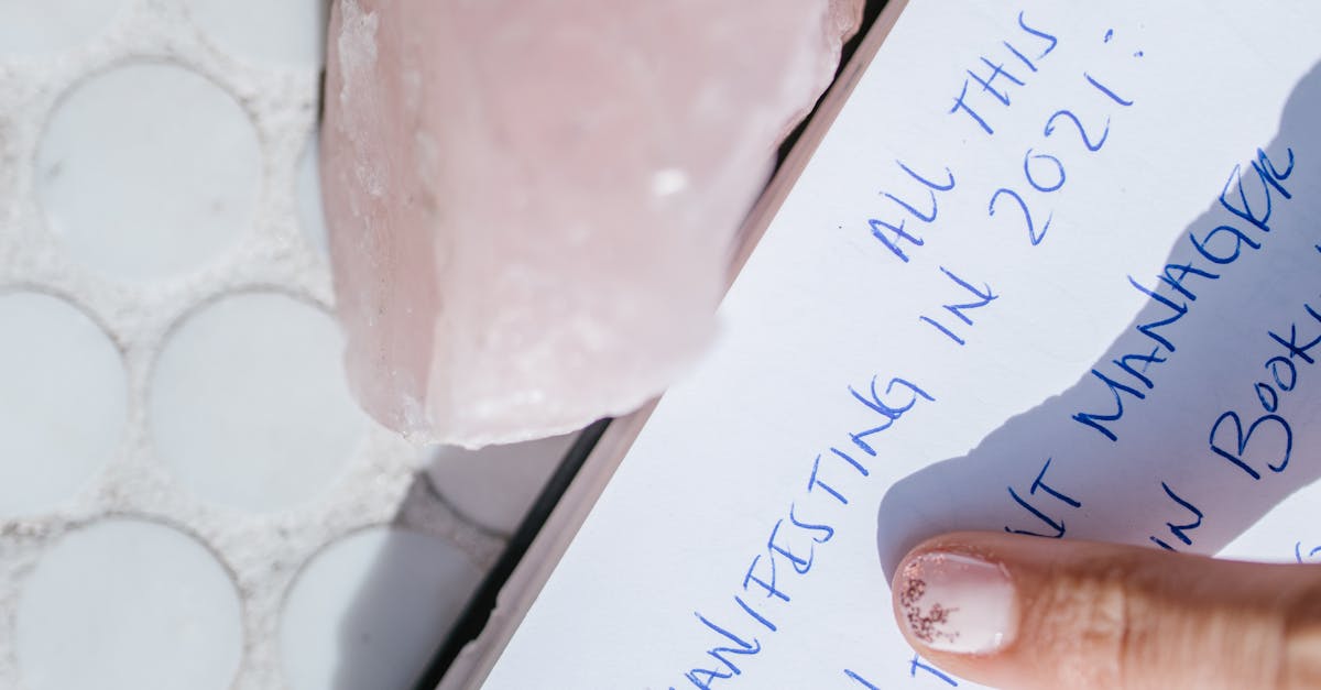 Close-up of a manifestation journal page with a rose quartz crystal and finger pointing.