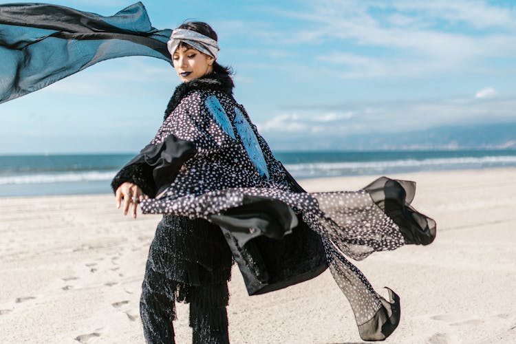 Woman In Black Outfit Standing On The Shore Of The Beach While Smiling At The Camera