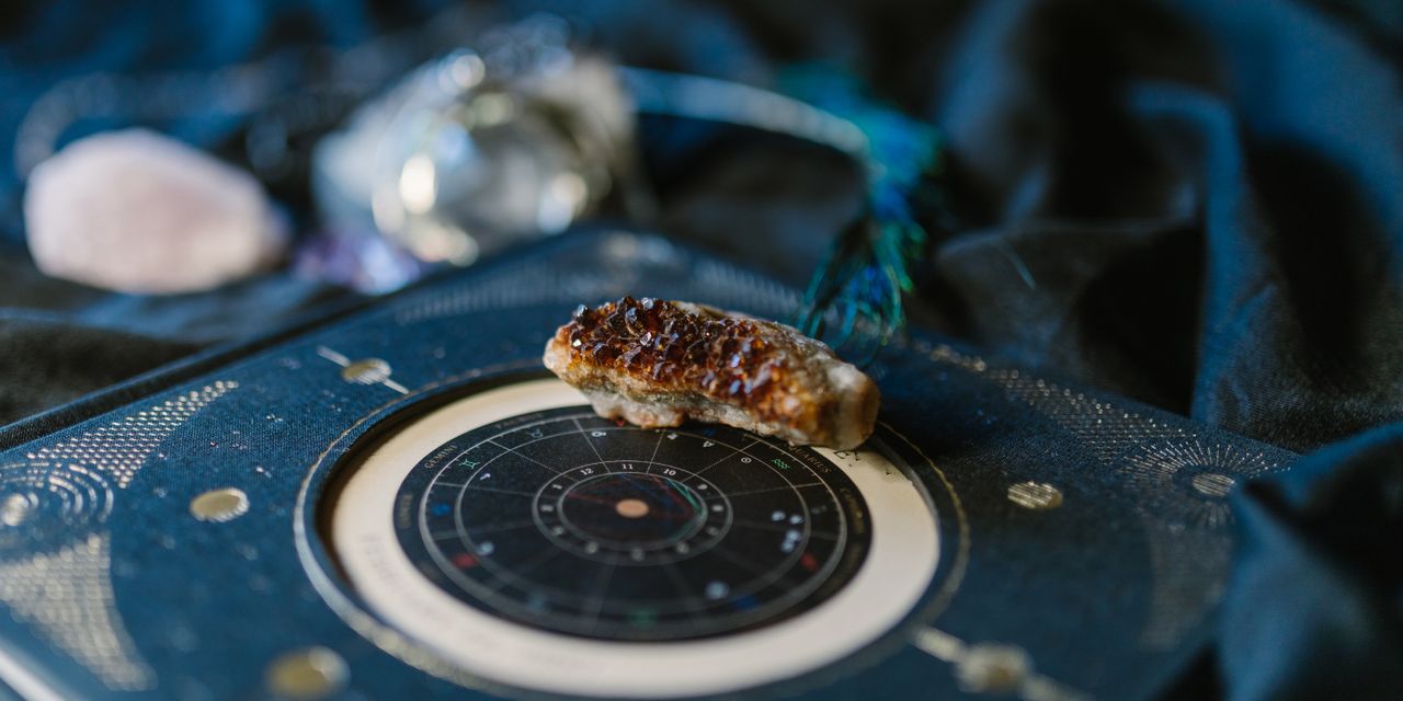 Close-up of crystals on an astrology chart atop dark fabric for a mystical vibe.