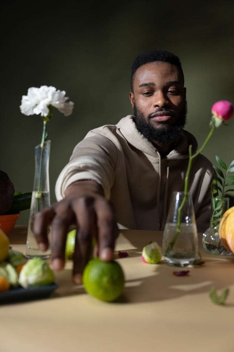 A Man In Beige Hoodie Holding A Fruit