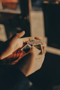 Close-up of hands gently holding a collection of vintage postage stamps, bathed in warm light.
