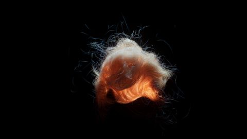 Surreal glowing light form with dynamic fibers, creating an abstract art piece.