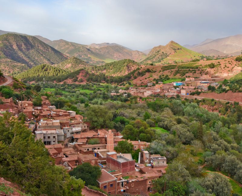 A picturesque hidden village in the Moroccan mountains, showcasing traditional architecture and lush greenery.