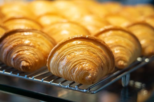 Delicious croissants on rack in pastry shop