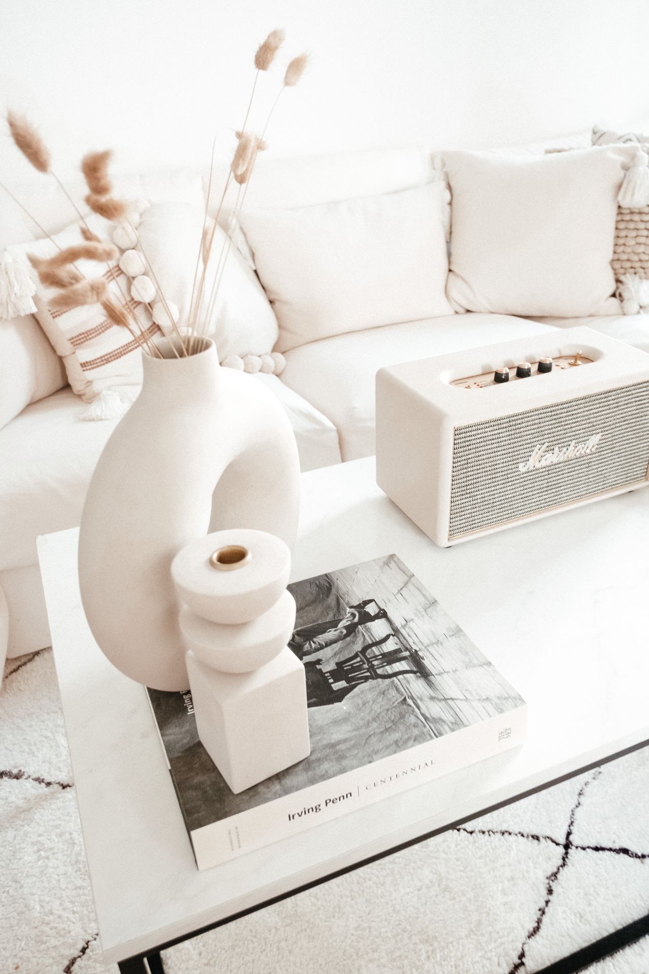 Styled white coffee table with vases, a book and a speaker