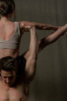Dynamic acrobatic yoga pose showcasing strength and balance between male and female partners.
