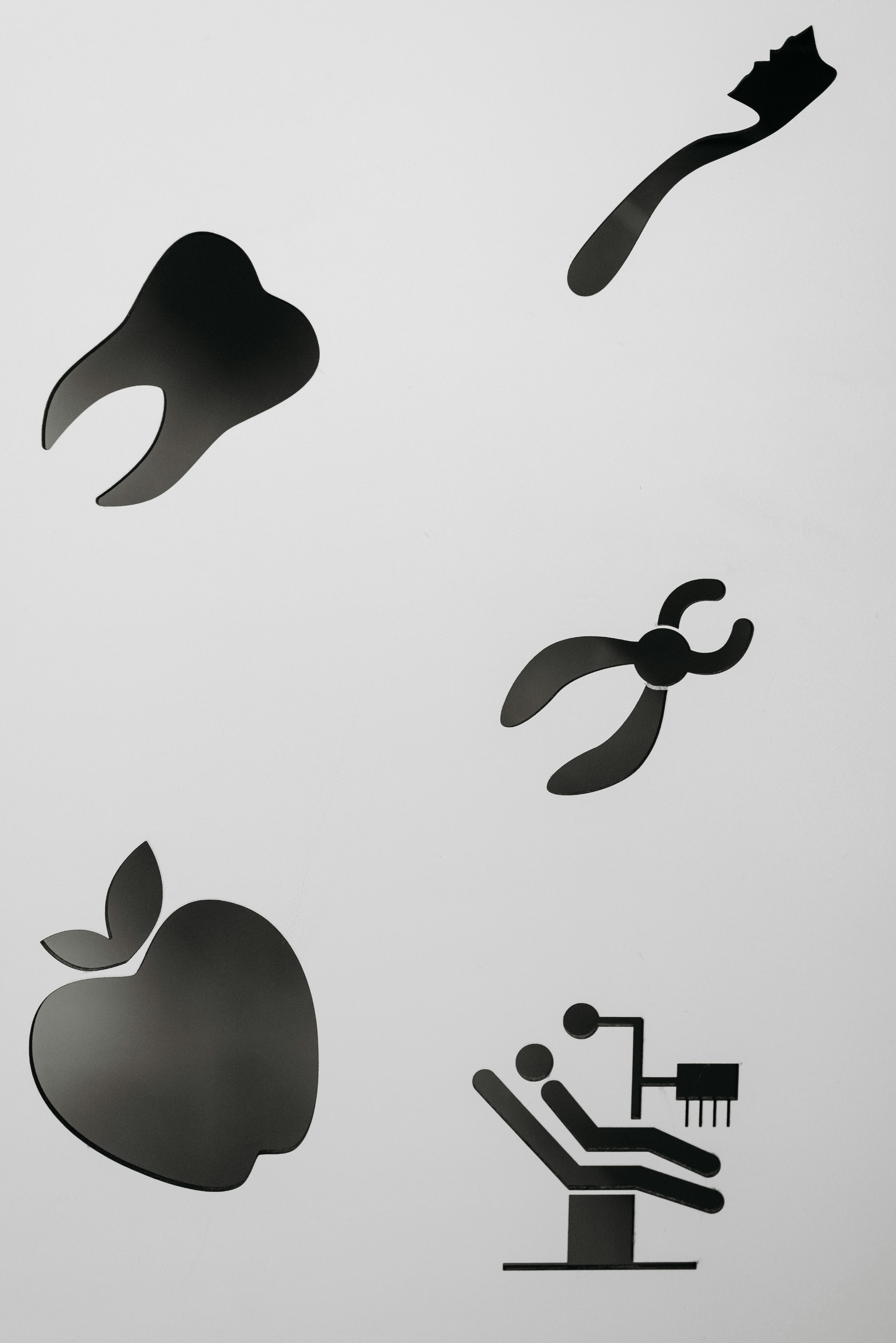 Silhouette cutouts of dental health symbols including tooth, apple, and dental chair on white background.