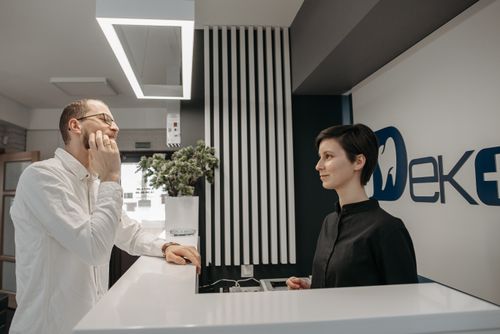 Free Patient discussing dental issues at a modern clinic reception with a receptionist. Stock Photo