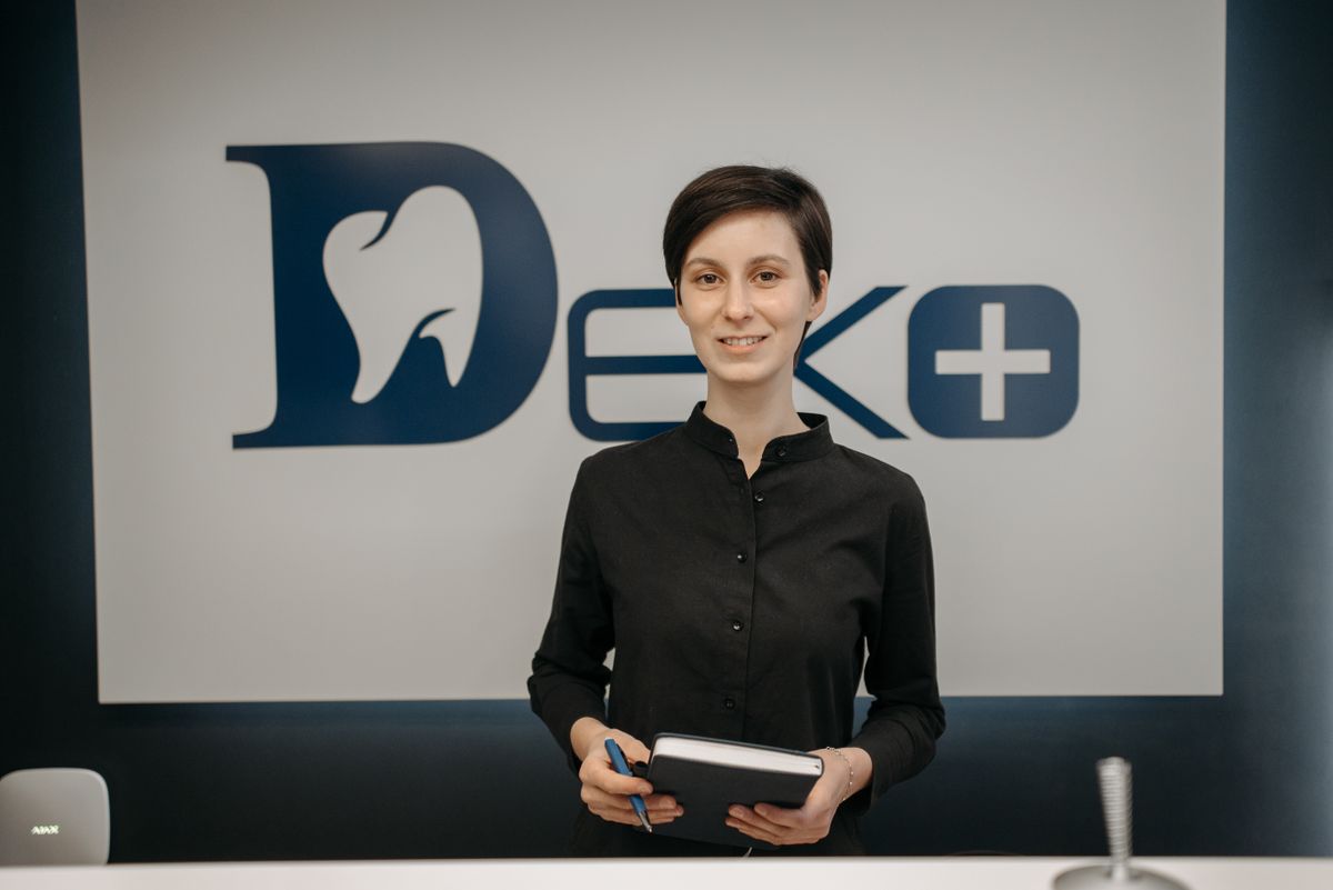 Dentist holding a notebook in front of a clinic sign