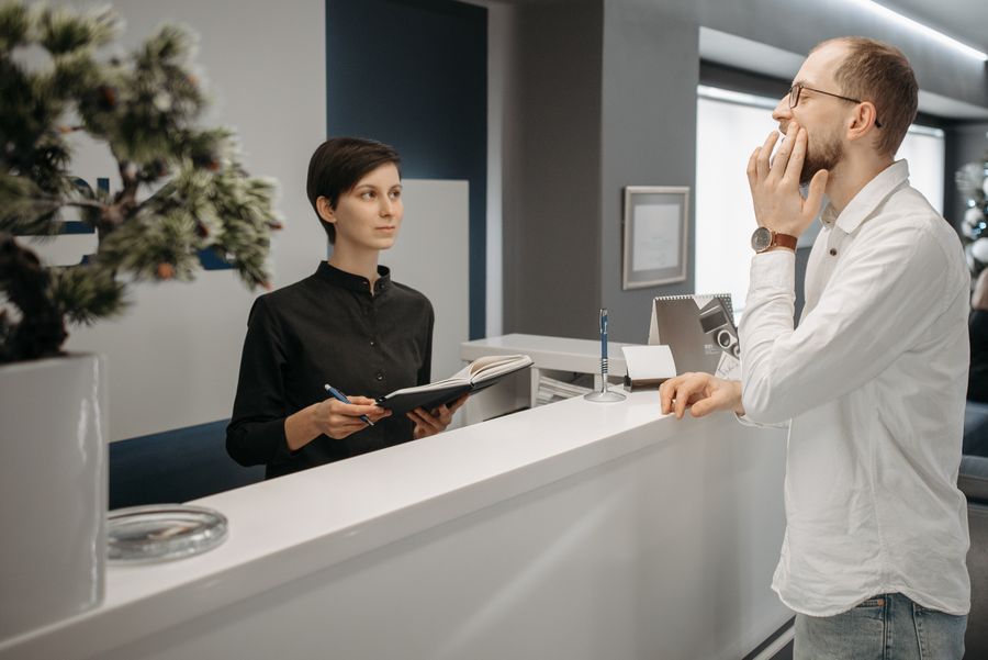 Patient with toothache speaking to the clinic receptionist
