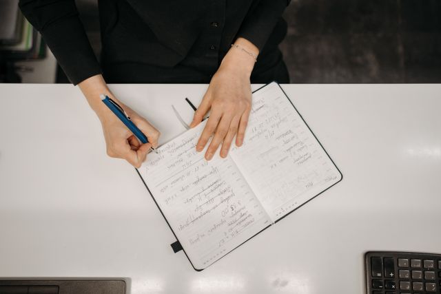 Hands writing in a research notebook at a desk — photo by Pavel Danilyuk on Pexels