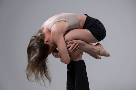 A powerful acrobatic pose with a woman supported by a partner, showcasing strength and flexibility.