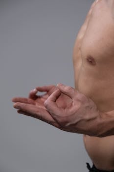 Close-up of a shirtless man practicing gyan mudra, symbolizing mindfulness and meditation.