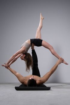 A man and woman perform an impressive acrobatic pose during a studio training session.