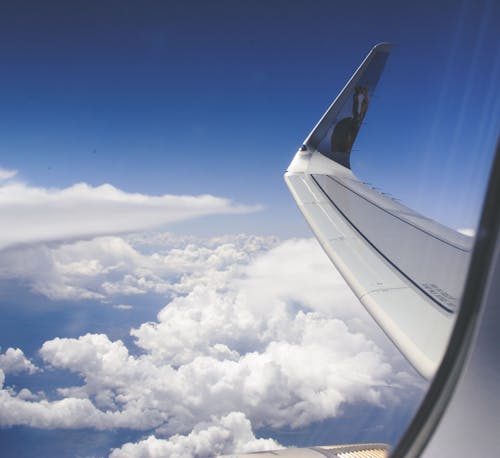 Hoge Hoekfoto Van Vliegtuigvleugels Boven De Wolken Onder Een Heldere Blauwe Hemel