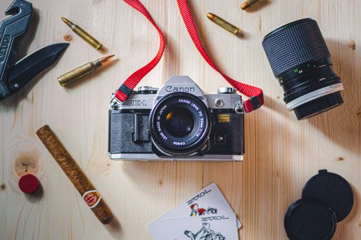 Vintage Canon camera with accessories on wooden surface. Aesthetic still life composition.