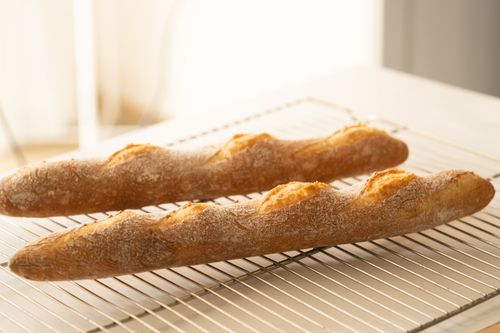 Free Golden brown baguettes cooling on rack, highlighting artisanal bakery quality. Stock Photo
