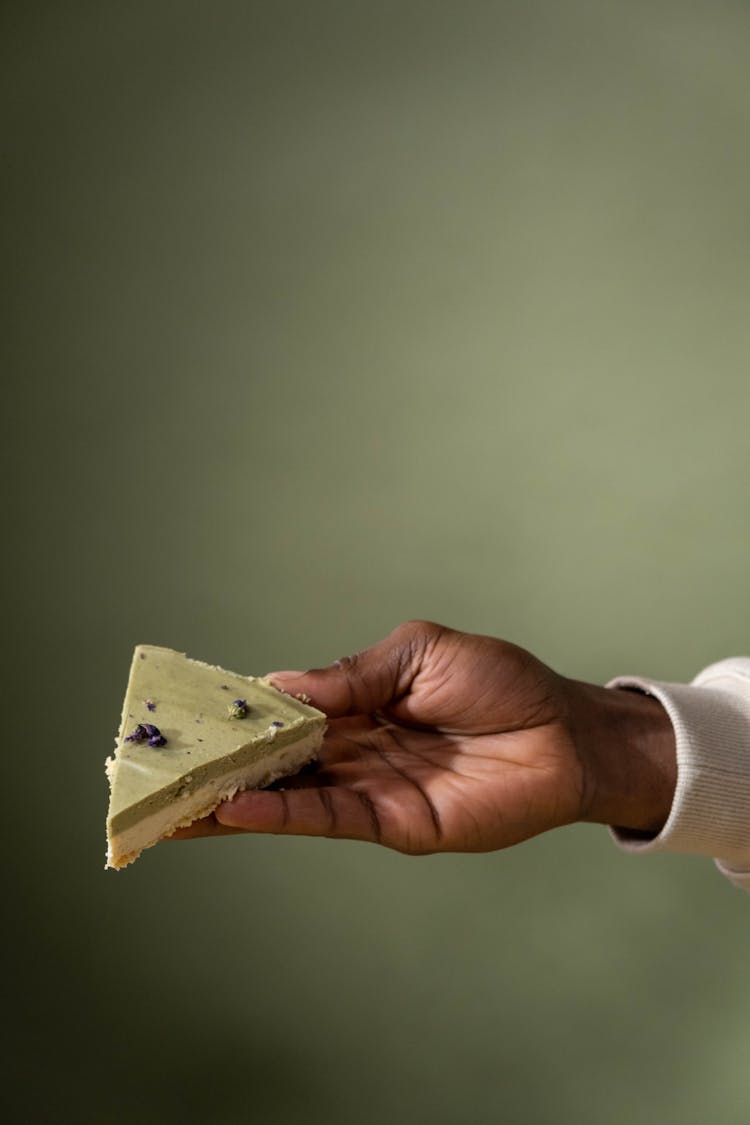 A Person Holding A Piece Of Layered Cake