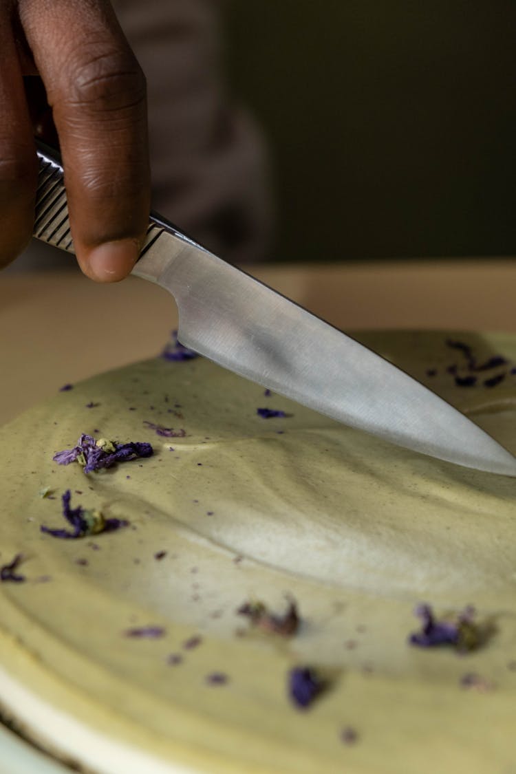 A Person Slicing A Layered Cake