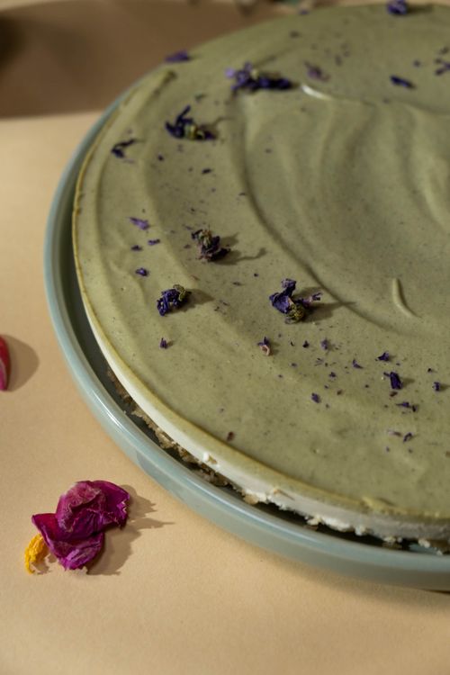 Free A delicious matcha cake adorned with purple flower petals, perfect for a special occasion. Stock Photo