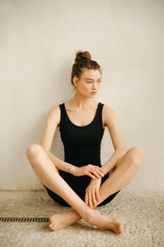 A serene woman poses in a minimal indoor setting, exuding calmness.