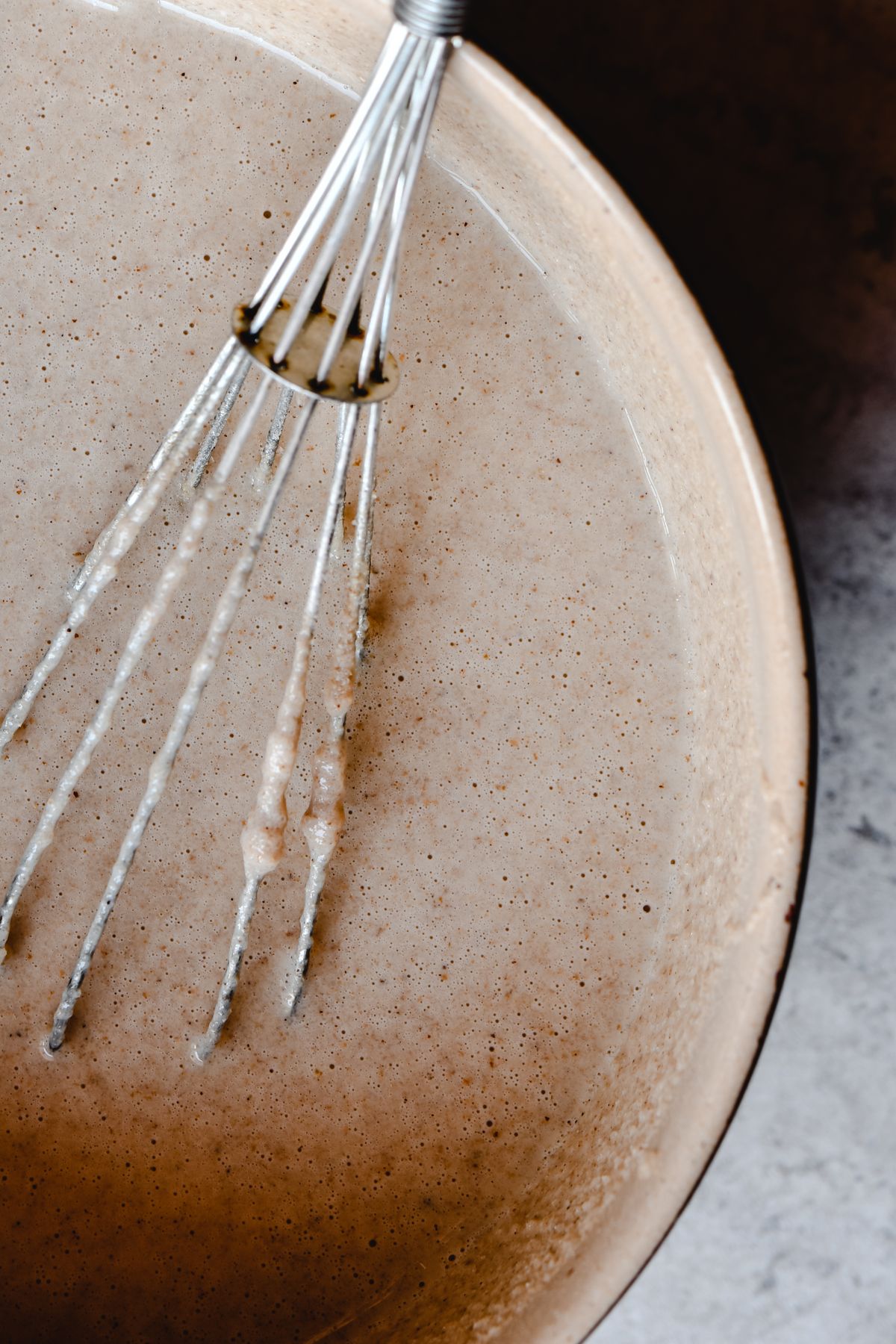 Pancake batter being gently mixed with a whisk in a ceramic bowl