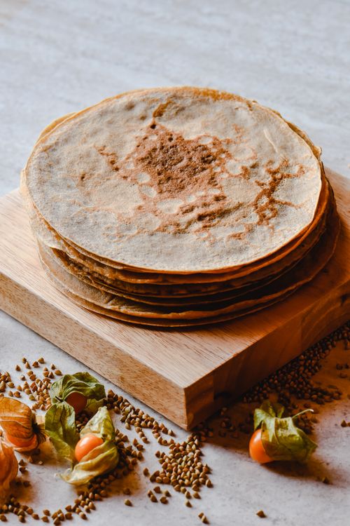Free Delicious homemade buckwheat pancakes stacked beautifully, surrounded by grains and fruits, perfect for a cozy breakfast vibe. Stock Photo
