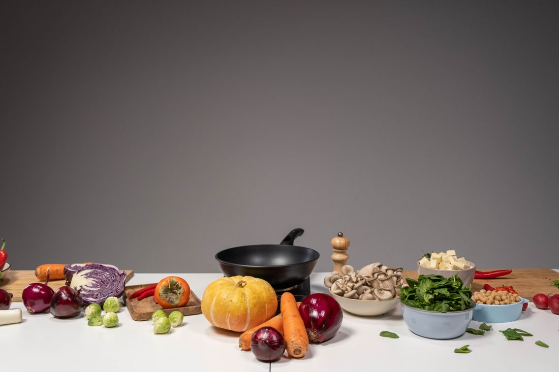 Fresh vegetables, legumes and a pan arranged for home cooking