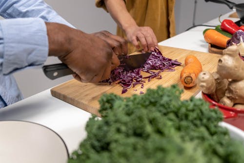 Free Person Slicing Red Cabbage on Wooden Chopping Board Stock Photo