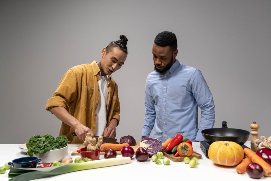 Two men preparing fresh vegetables, showcasing healthy vegan food options. Two men preparing fresh vegetables, showcasing healthy vegan food options.