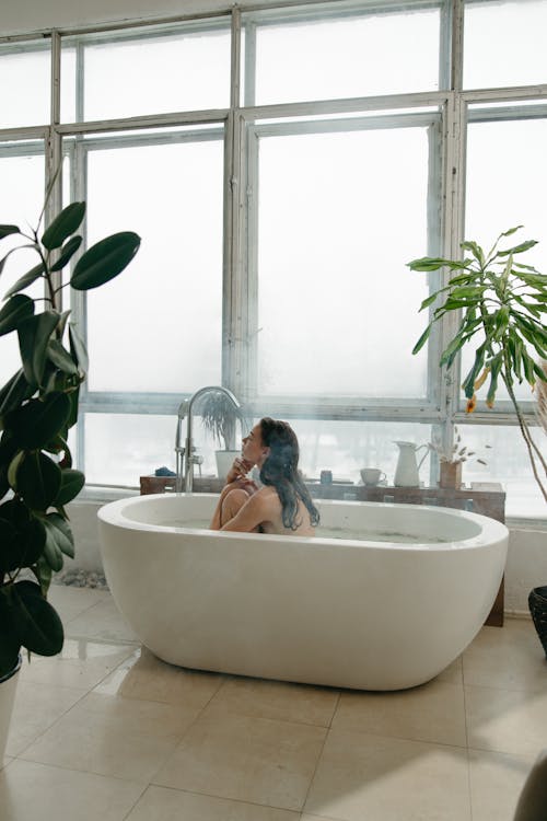 Free Woman Bathing in Bathtub Near Window Glass Stock Photo