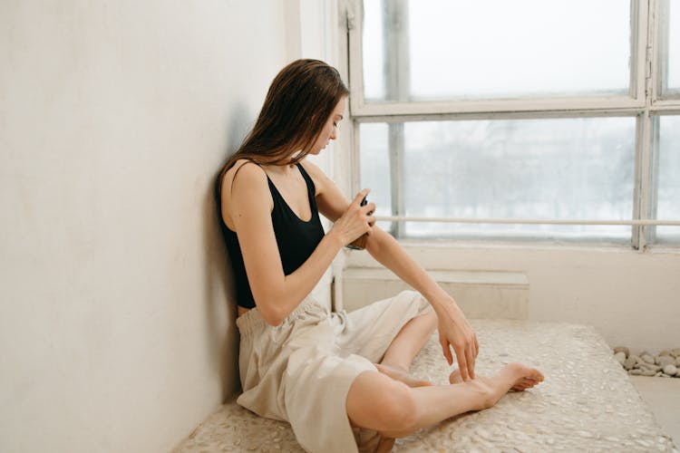 A Woman Applying Lotion On Her Arm