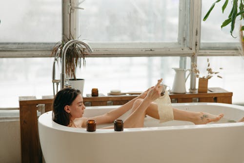 Woman in Bathtub Scrubbing Her Leg