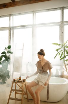 Woman seated by a bathtub enjoying a serene and steamy atmosphere indoors.
