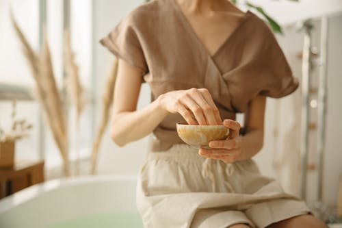 Woman in Brown Button Up Shirt Sitting on White Bathtub