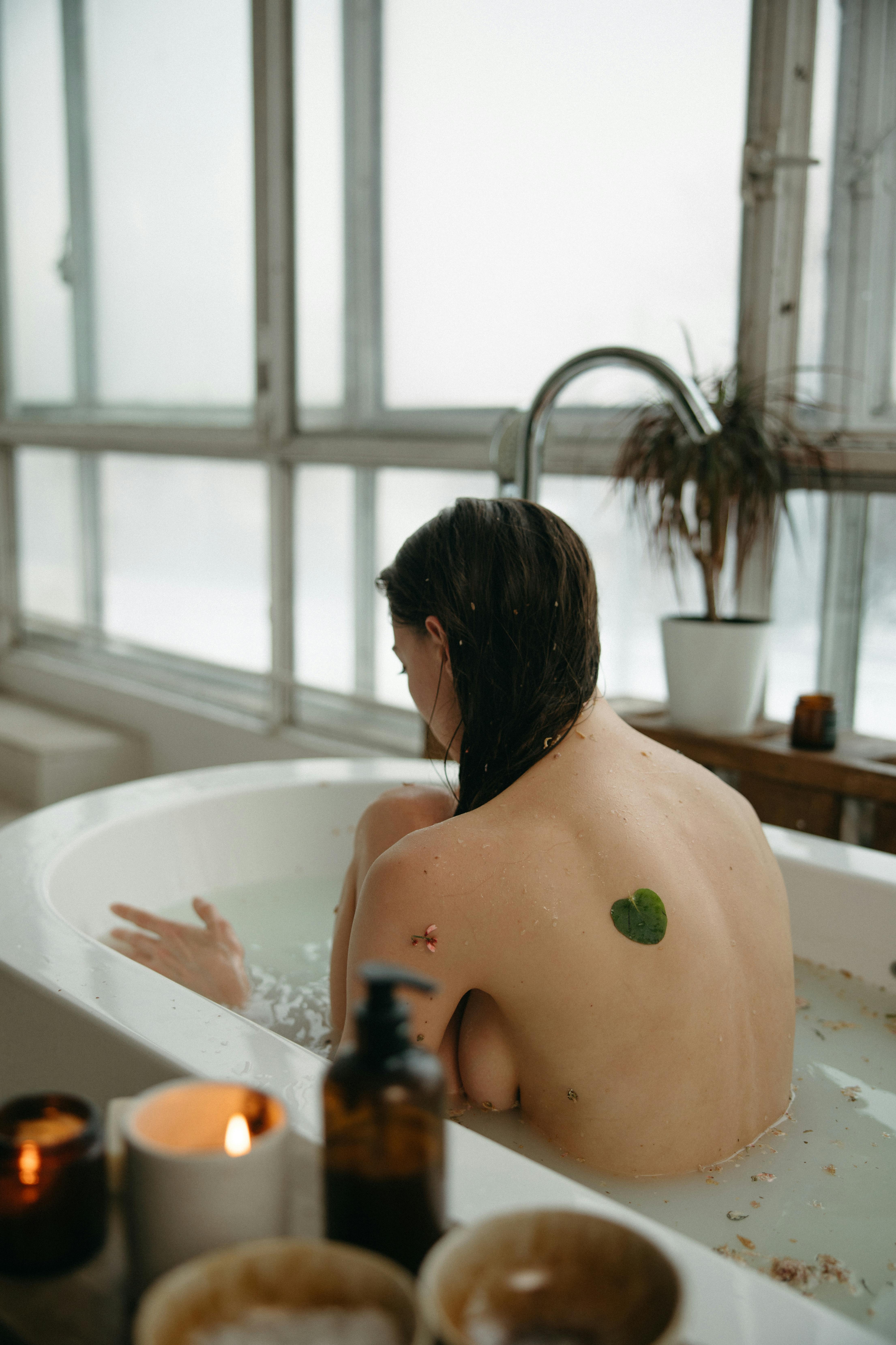 naked woman sitting in bathtub