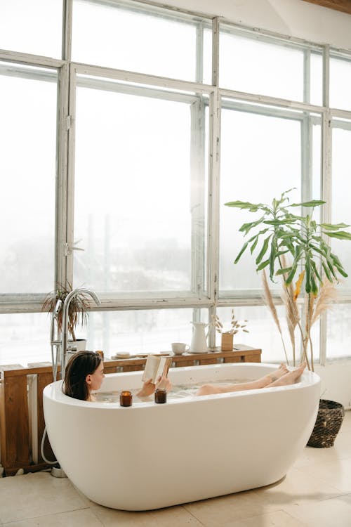 Woman Reading a Book While Lying in Bathtub