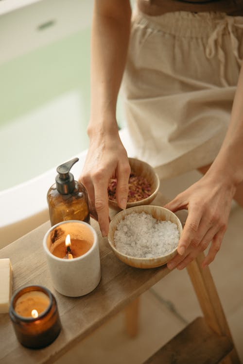 An image of a person holding a wooden bowl of salt