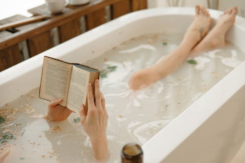 Free A Person Reading a Book while Bathing in a Bathtub Stock Photo