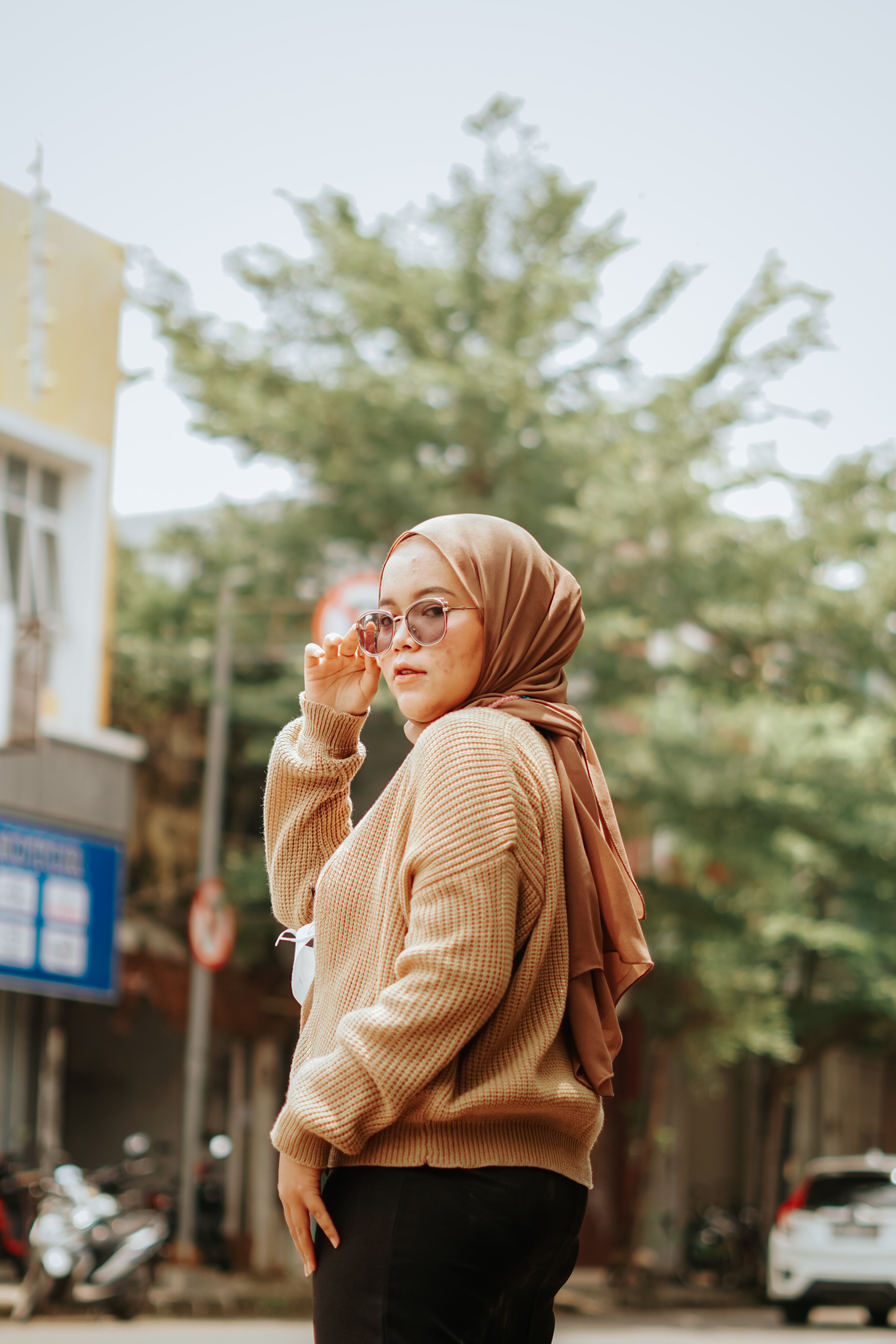 Elegant Muslim woman wearing sunglasses and hijab posing on a street in Jawa Barat, Indonesia.