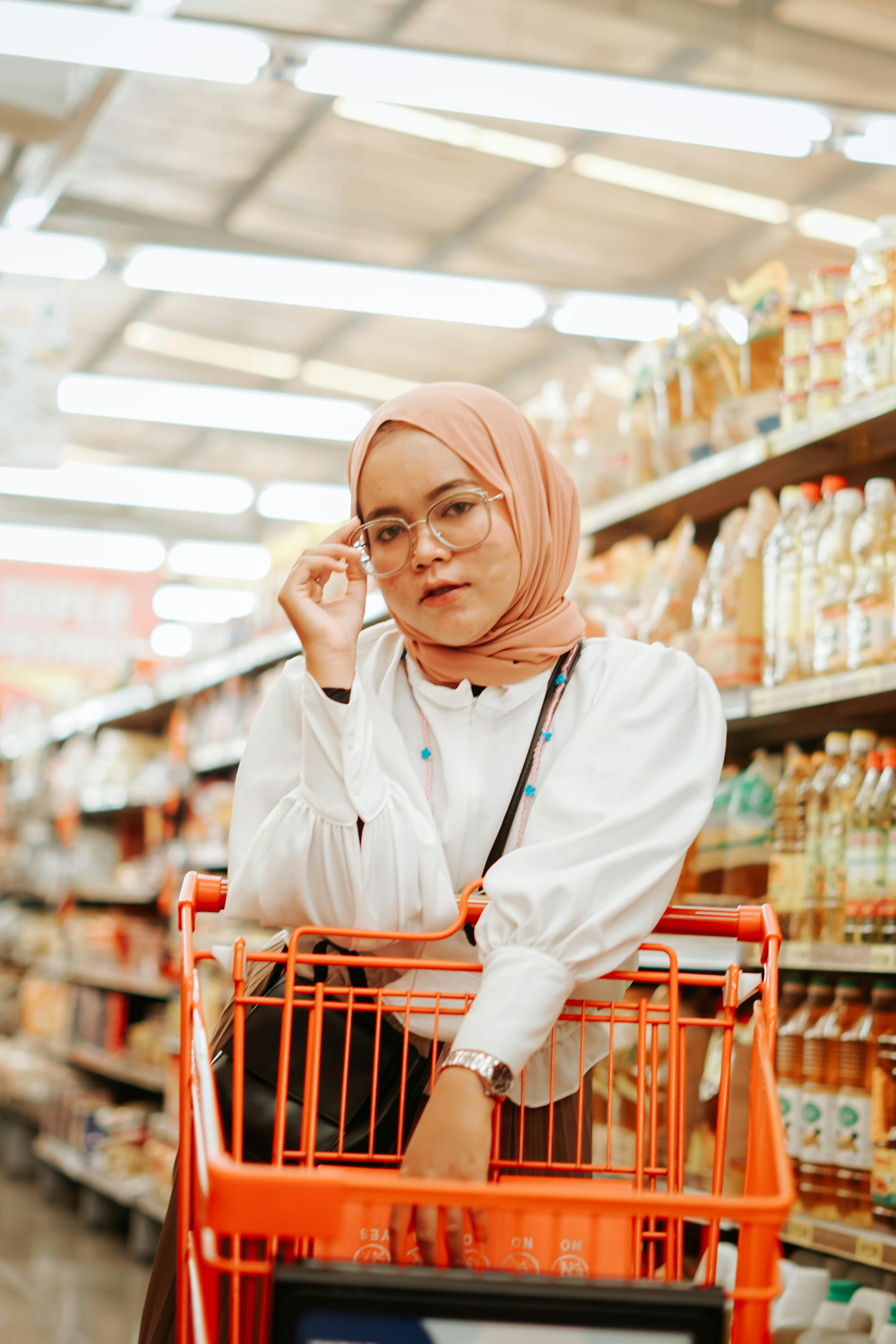 Portrait of a woman with a shopping cart in an Indonesian supermarket aisle.