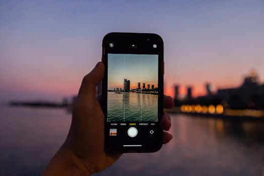 Hand holding smartphone capturing Shenzhen skyline during vibrant twilight.