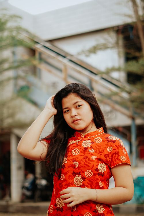 Free A teenager wearing a traditional red cheongsam poses outdoors in Cirebon, Indonesia. Stock Photo